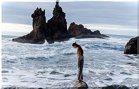 Girl on a rock and rough sea.