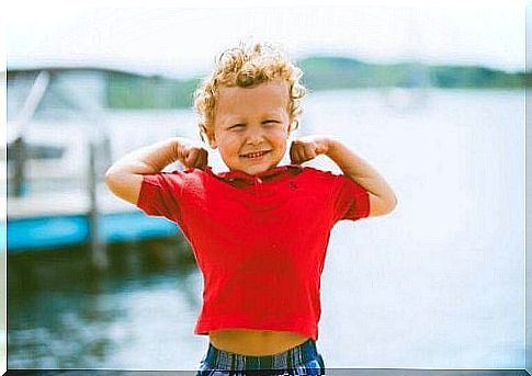 Blond child with arms flexed to show muscles