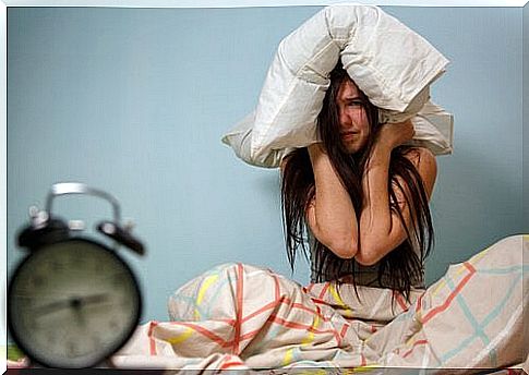 Teenager with pillow on her head and alarm clock