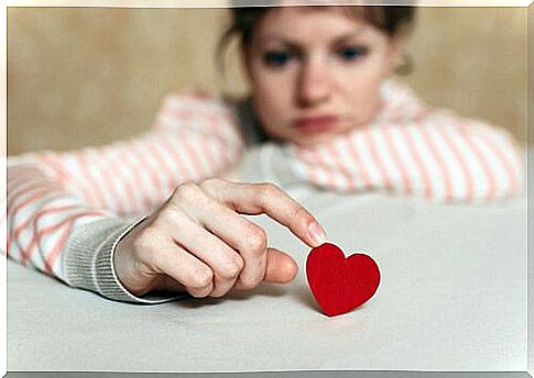 Sad woman touching paper heart