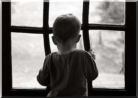 Sad and lonely child looking out the window.