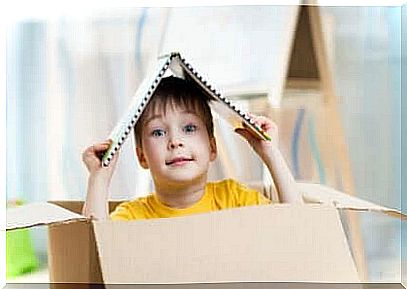 Child plays inside a paper carton.