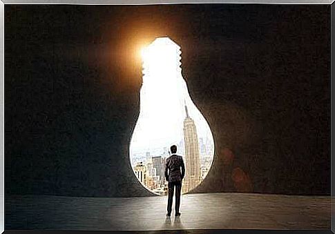 Man in front of a door to the world in the shape of a light bulb.