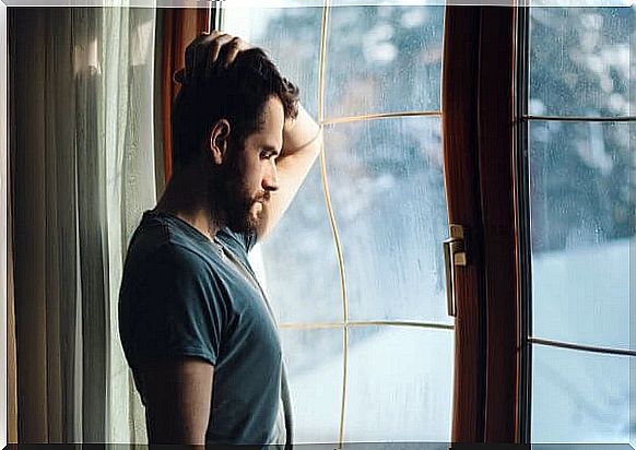 Sad man standing by the window