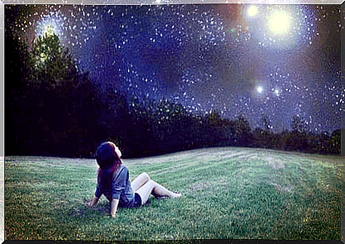 Little girl sitting on the grass looking at the sky and discovering her star